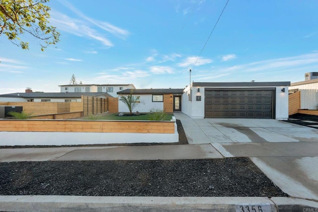 view of front of home featuring a garage, driveway, and fence