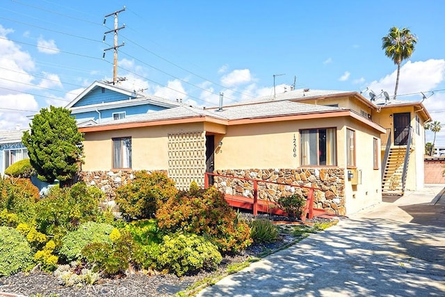 view of home's exterior with stone siding, stairway, and stucco siding