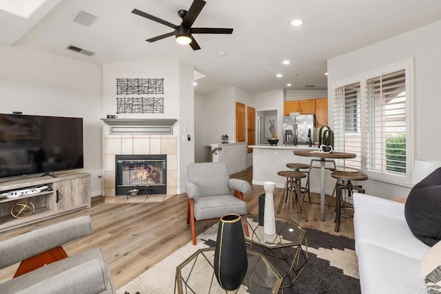 living area featuring visible vents, a tile fireplace, ceiling fan, light wood-type flooring, and recessed lighting