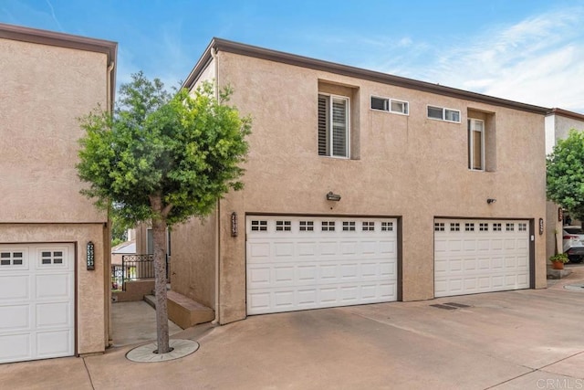 view of front of house with a garage, concrete driveway, and stucco siding