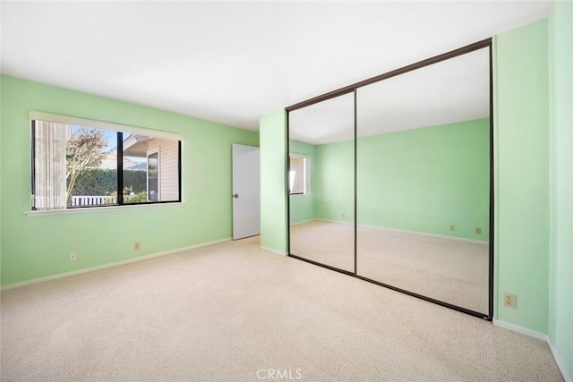 unfurnished bedroom with a closet, carpet flooring, and baseboards