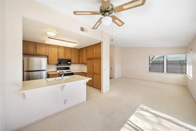 kitchen with visible vents, brown cabinetry, freestanding refrigerator, light countertops, and black microwave