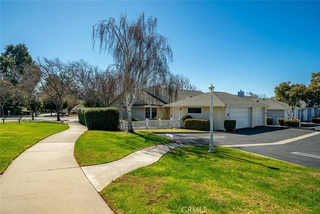 view of front of home with a garage, a front lawn, and fence