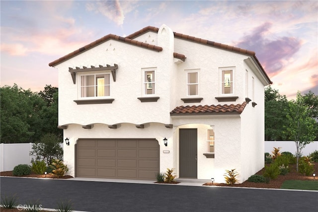 mediterranean / spanish-style house with a garage, fence, a tiled roof, and stucco siding