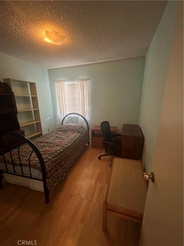 bedroom with a textured ceiling and light wood-style floors