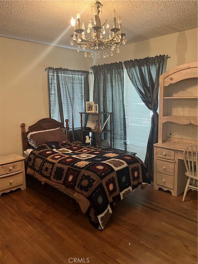 bedroom with dark wood-type flooring, a notable chandelier, and a textured ceiling