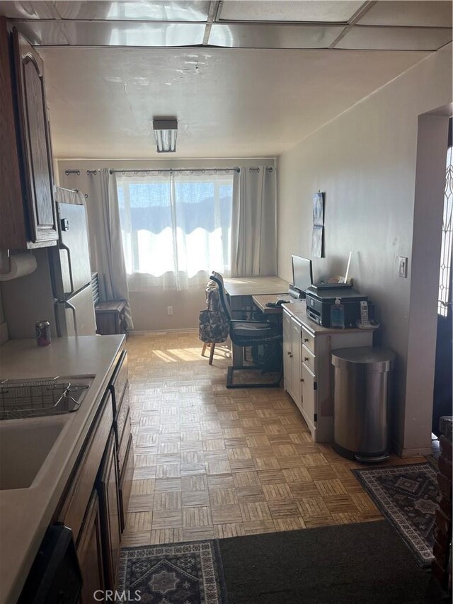 kitchen with dark brown cabinetry, light countertops, a sink, and freestanding refrigerator