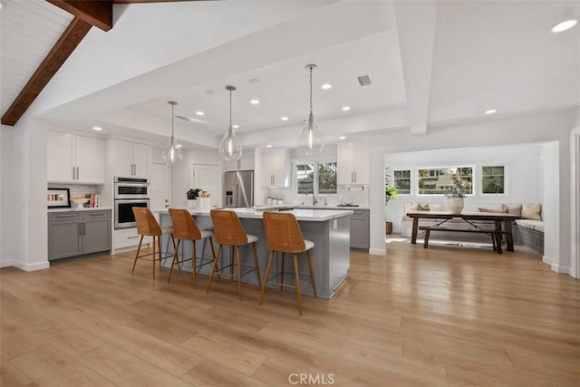 kitchen with white cabinets, light countertops, appliances with stainless steel finishes, hanging light fixtures, and a large island
