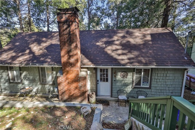 view of front of house with roof with shingles and a chimney