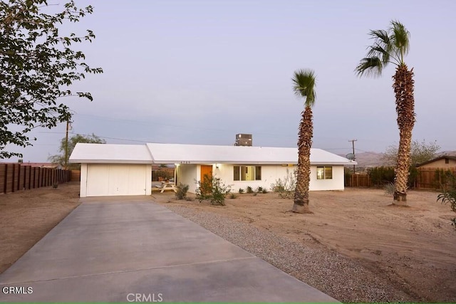 single story home featuring concrete driveway and fence