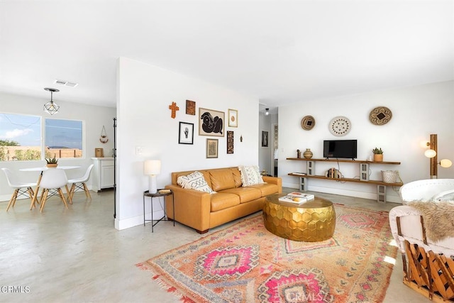 living room featuring visible vents, concrete floors, and baseboards