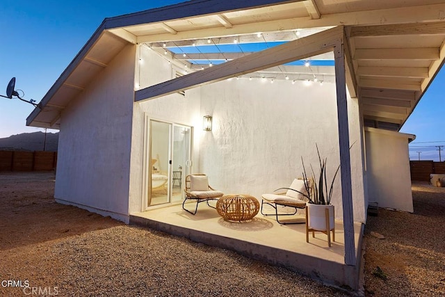 exterior space with a patio area, fence, and stucco siding