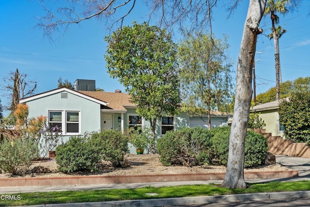 ranch-style house with roof with shingles and stucco siding