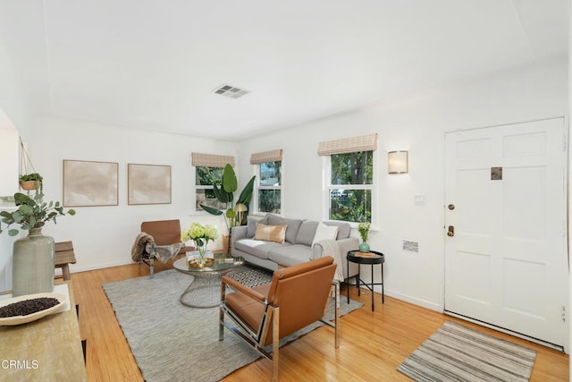 living room with wood finished floors, visible vents, and baseboards