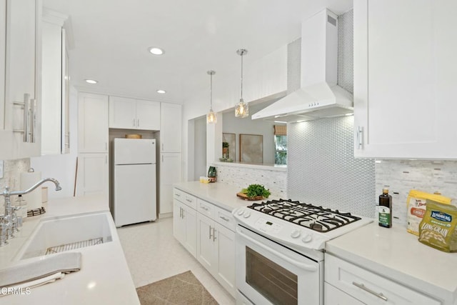 kitchen featuring white appliances, white cabinets, wall chimney exhaust hood, light countertops, and a sink