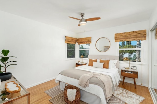 bedroom featuring ceiling fan, multiple windows, light wood-type flooring, and baseboards