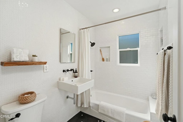 bathroom featuring shower / bath combination with curtain, a sink, and toilet