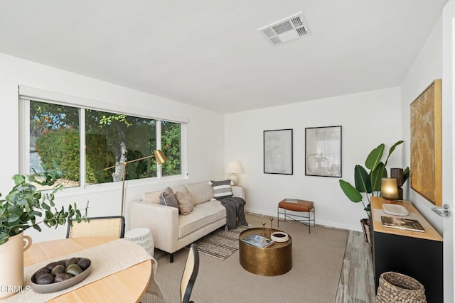 living area with visible vents, light wood finished floors, and baseboards