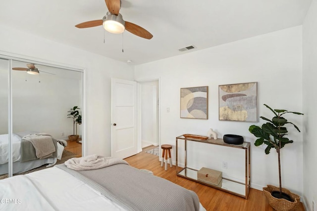 bedroom featuring light wood finished floors, a ceiling fan, visible vents, and a closet