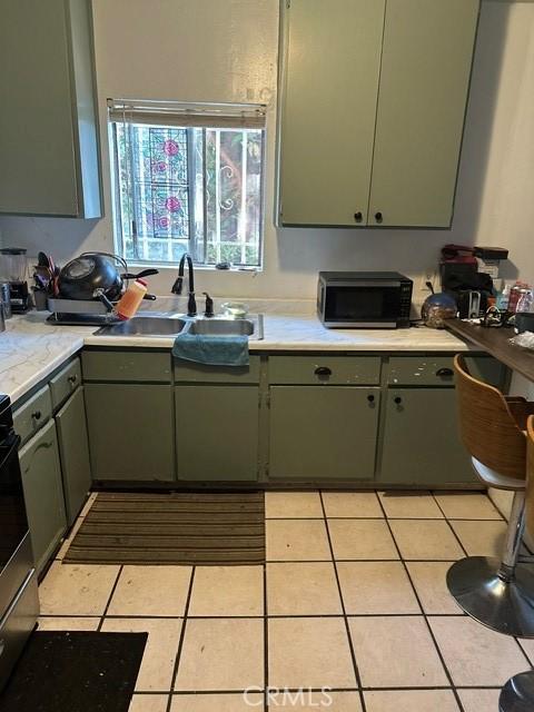 201 W Raymond St, Compton, CA 90220 - kitchen featuring black microwave, light countertops, electric range, and light tile patterned floors