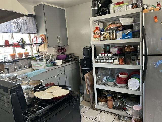 201 W Raymond St, Compton, CA 90220 - kitchen with freestanding refrigerator, gray cabinetry, and light tile patterned flooring