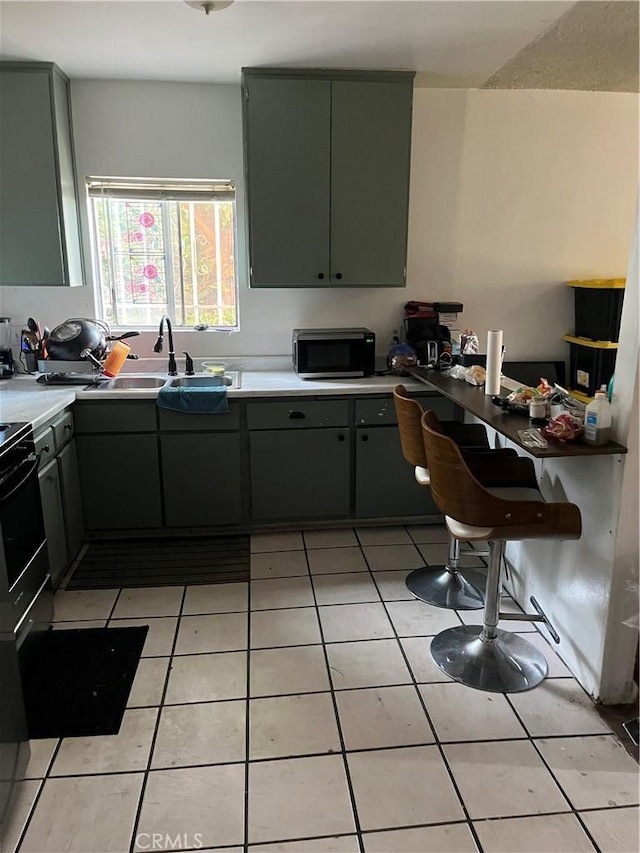 201 W Raymond St, Compton, CA 90220 - kitchen featuring stainless steel microwave, gray cabinets, light tile patterned flooring, and light countertops
