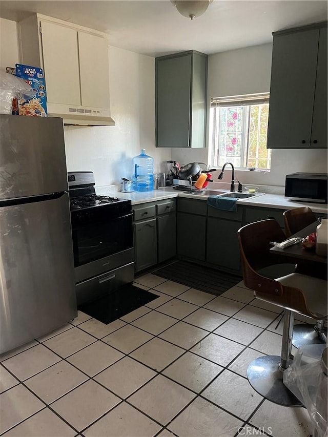 201 W Raymond St, Compton, CA 90220 - kitchen featuring stainless steel appliances, under cabinet range hood, light tile patterned floors, light countertops, and gray cabinets