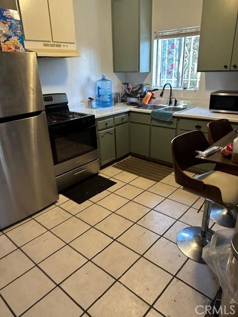 201 W Raymond St, Compton, CA 90220 - kitchen with appliances with stainless steel finishes, under cabinet range hood, light countertops, and light tile patterned floors