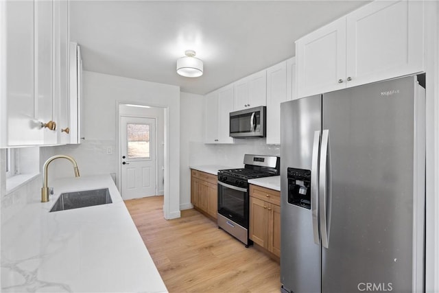 kitchen featuring white cabinetry, appliances with stainless steel finishes, brown cabinetry, and a sink