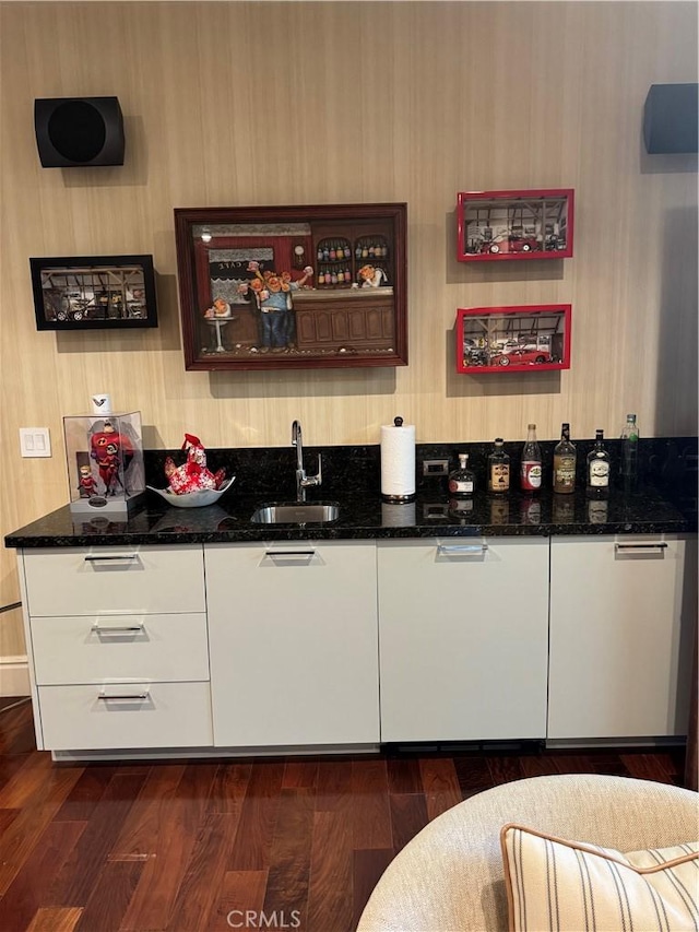 bar with dark wood-style floors, wet bar, and a sink