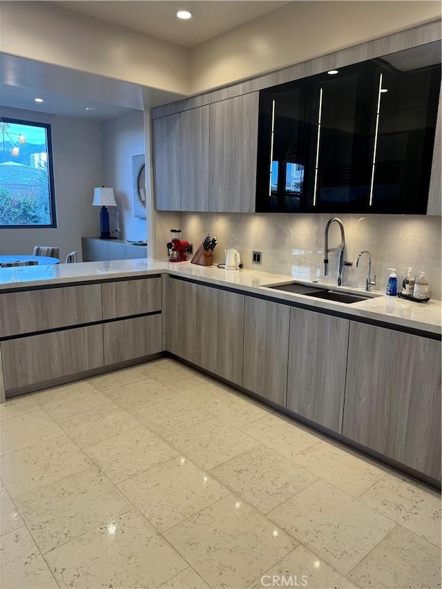 kitchen with light countertops, modern cabinets, a sink, and decorative backsplash