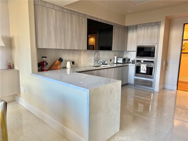 kitchen with tasteful backsplash, modern cabinets, built in microwave, stainless steel oven, and a sink