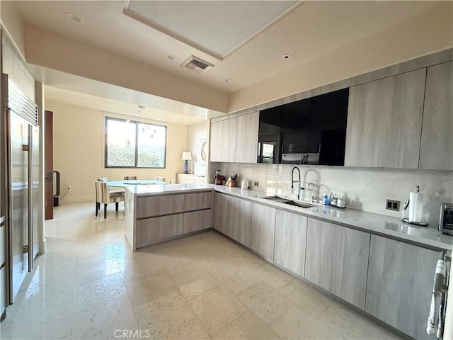 kitchen with backsplash, modern cabinets, a sink, and visible vents