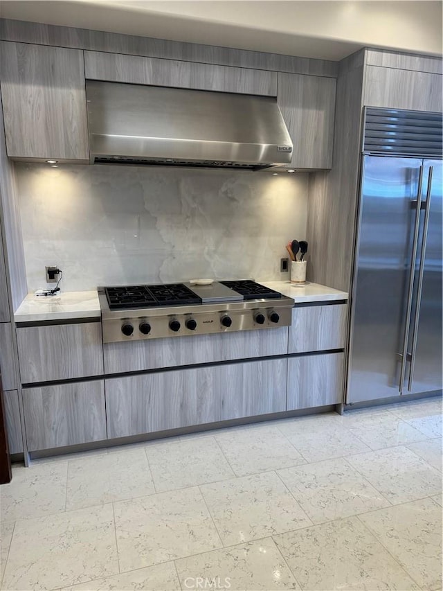 kitchen featuring decorative backsplash, appliances with stainless steel finishes, light countertops, and ventilation hood