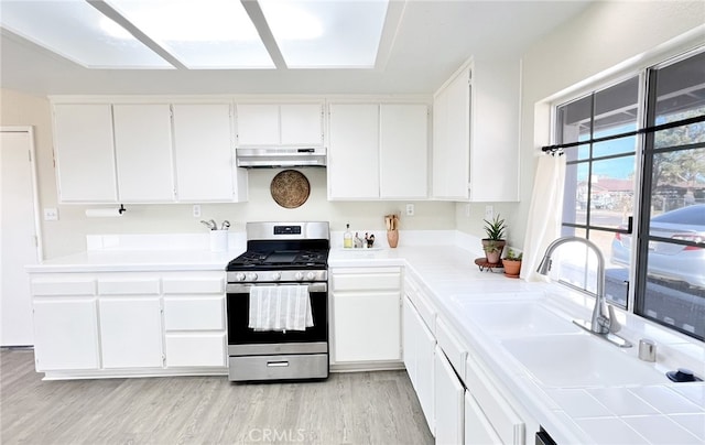 40661 169th St E, Lancaster, CA 93535 - kitchen with stainless steel gas range oven, under cabinet range hood, white cabinets, light wood-type flooring, and a sink