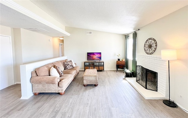 living area featuring a textured ceiling, a fireplace, baseboards, and wood finished floors