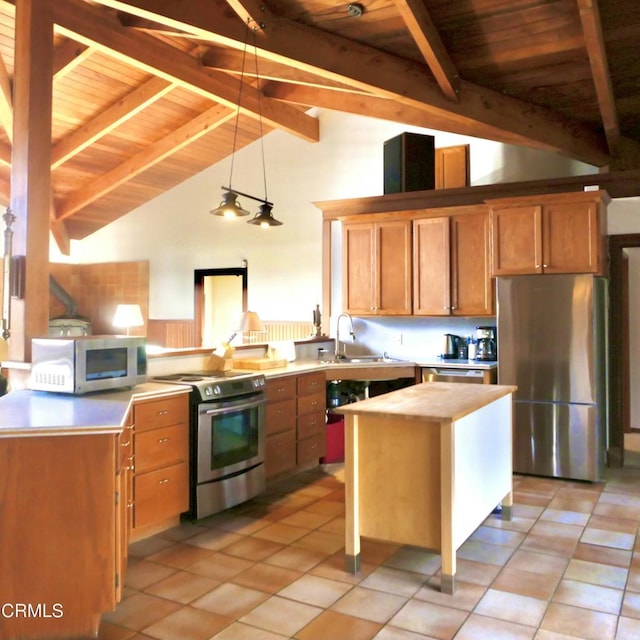 kitchen featuring lofted ceiling with beams, decorative light fixtures, a center island, stainless steel appliances, and a sink