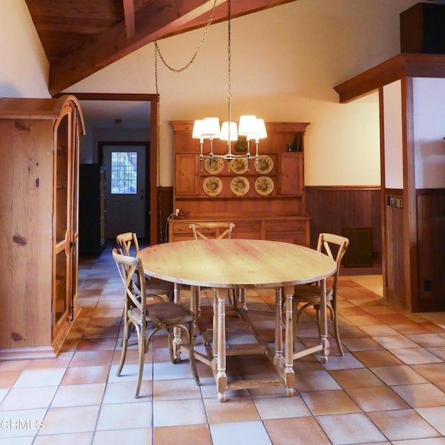 dining space featuring light tile patterned floors, lofted ceiling with beams, wainscoting, wood walls, and a chandelier