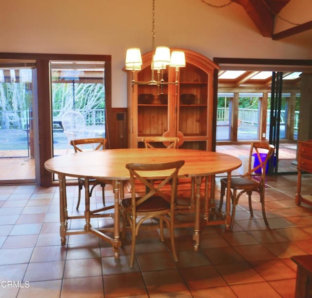 dining area with a wainscoted wall, plenty of natural light, an inviting chandelier, and tile patterned floors