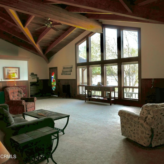 living room featuring high vaulted ceiling, a wainscoted wall, beamed ceiling, and carpet flooring