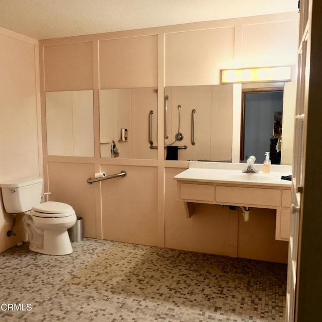 bathroom featuring toilet, a decorative wall, and a sink