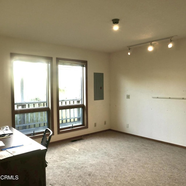 home office featuring visible vents, baseboards, electric panel, and light colored carpet