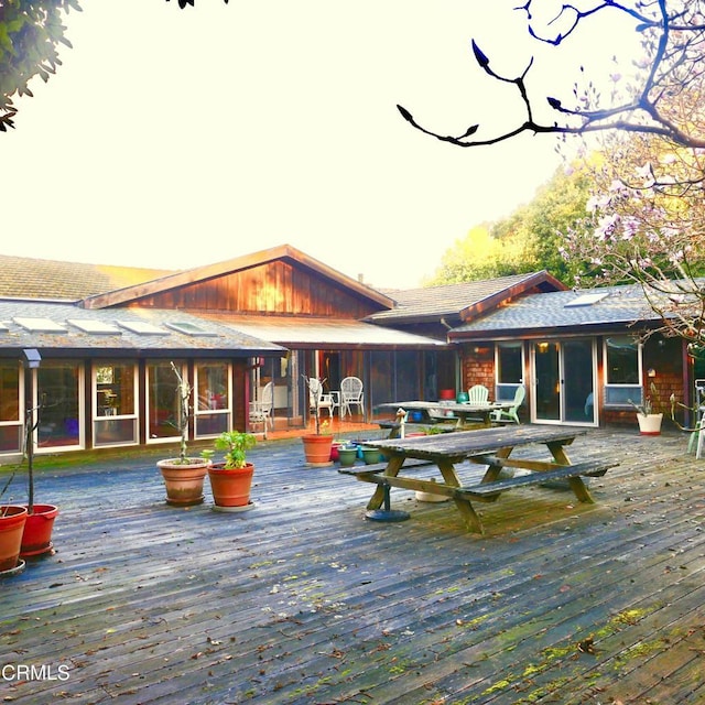 back of house featuring outdoor dining space, a sunroom, and a wooden deck