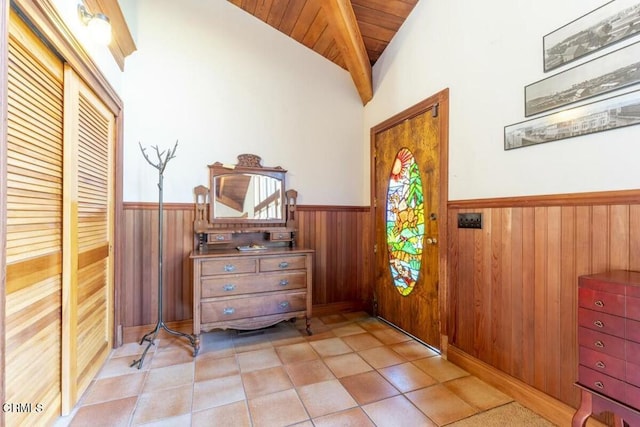 foyer entrance featuring wood ceiling, wainscoting, wood walls, light tile patterned flooring, and lofted ceiling