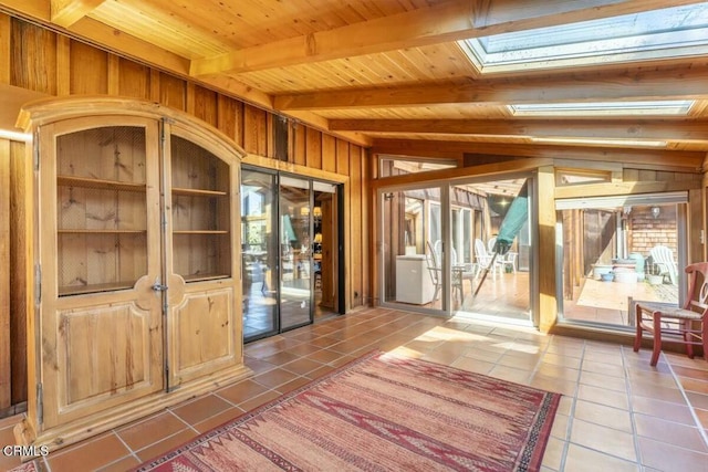 interior space featuring vaulted ceiling with skylight, tile patterned floors, wooden ceiling, and a healthy amount of sunlight