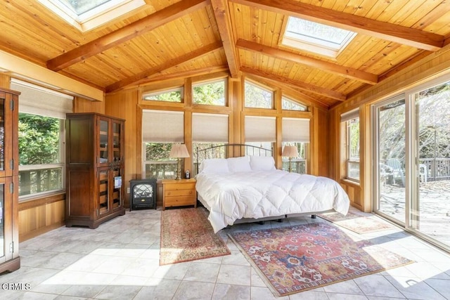 bedroom featuring vaulted ceiling with skylight, access to exterior, wooden walls, and multiple windows