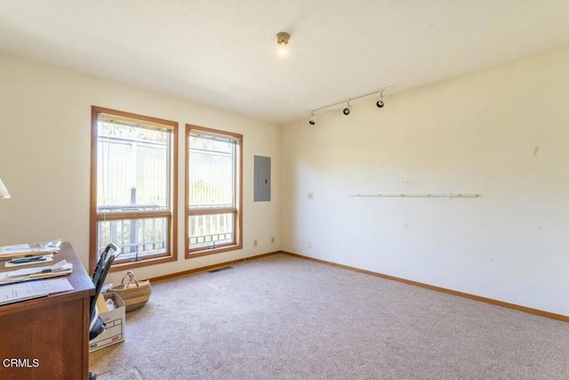 unfurnished office with visible vents, baseboards, track lighting, electric panel, and light carpet