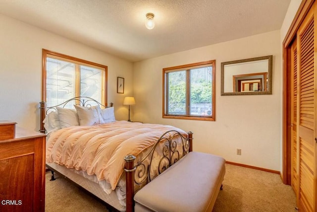 carpeted bedroom featuring a closet, baseboards, and a textured ceiling