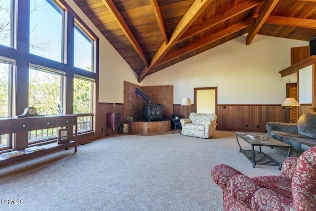 living area with wooden ceiling, a wood stove, beamed ceiling, wainscoting, and carpet flooring