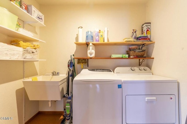 washroom featuring laundry area, a sink, baseboards, and washer and clothes dryer